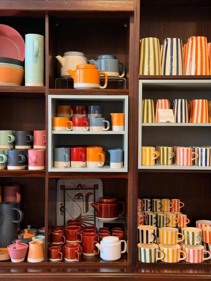 Colorful ceramic mugs and teapots displayed on shelves
